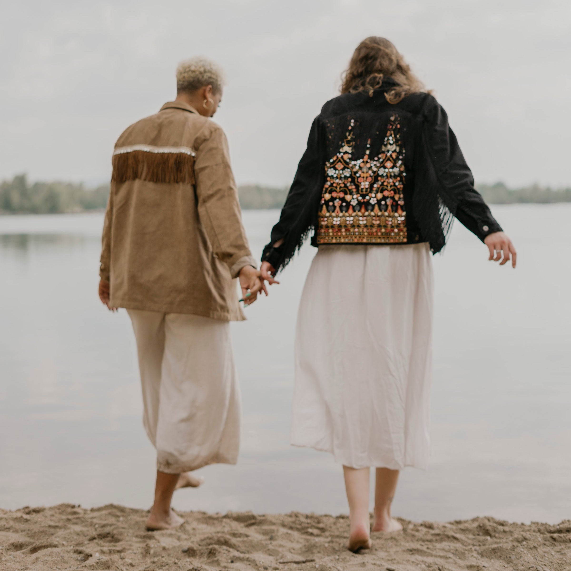 Bild von zwei Frauen am Wasser. Sie tragen Jacken im Boho-Stil