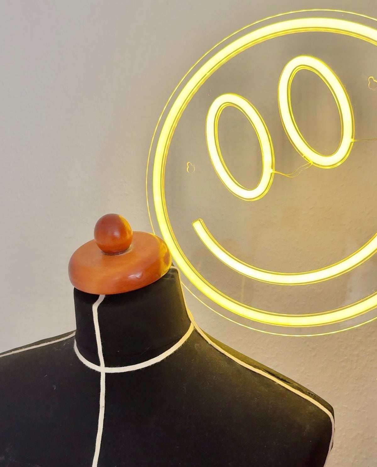 Bild von einer Schneiderbüste im Vintage-Stil. Im Hintergrund ist eine Smiley-Lampe in gelb zu sehen.