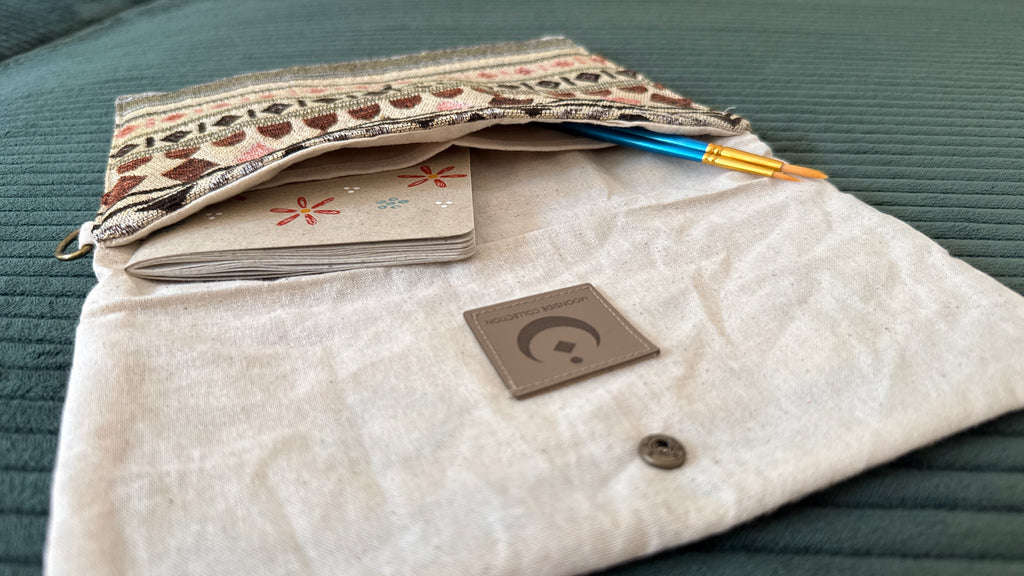 Offene Tasche mit Moonside Logo, Notizbuch und Pinseln