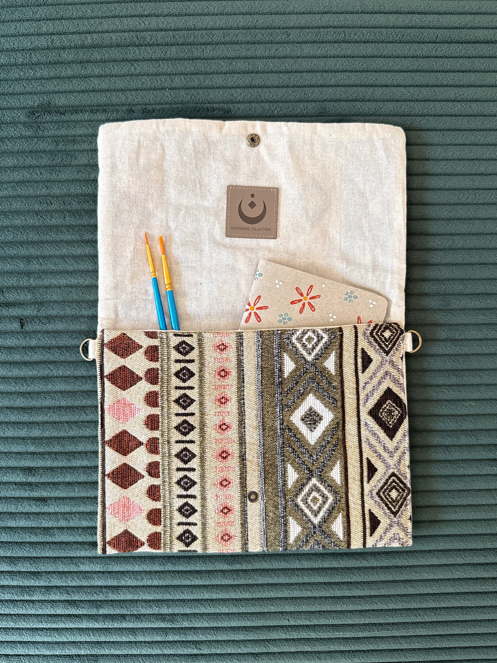 Offene Tasche im Bohostil mit Notizbuch und Pinseln